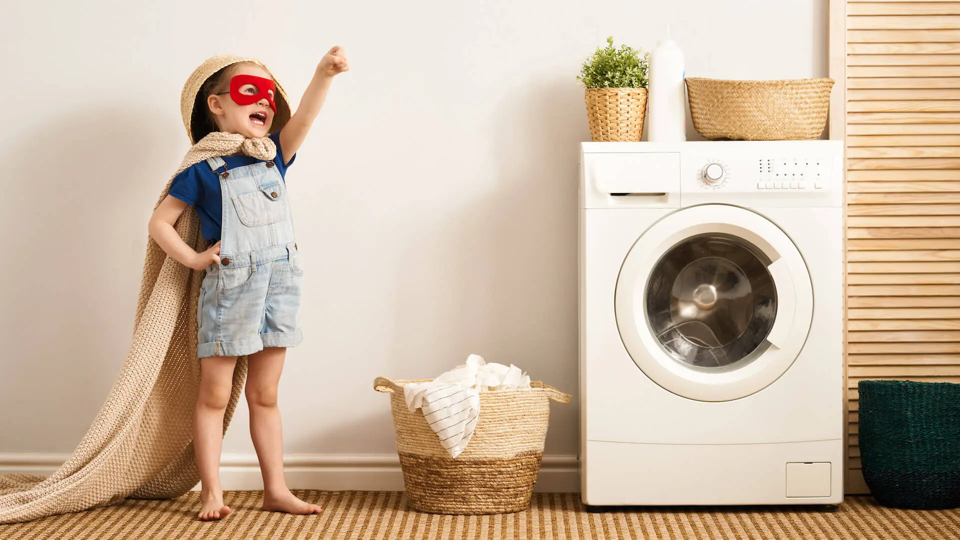 Little girl dressed as a hero in a laundry room